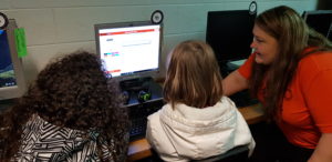 Teacher helping students on computer